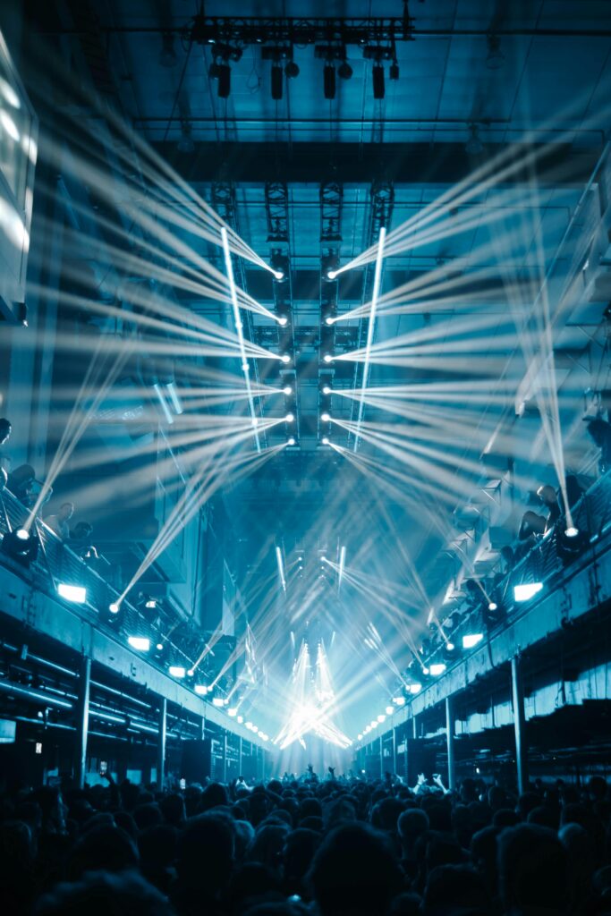 pexels-photo-16113684-16113684 Dynamic nightclub scene featuring dazzling light beams illuminating a vibrant concert crowd.